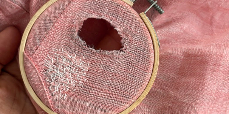 Person mending a garment by hand with needle and thread