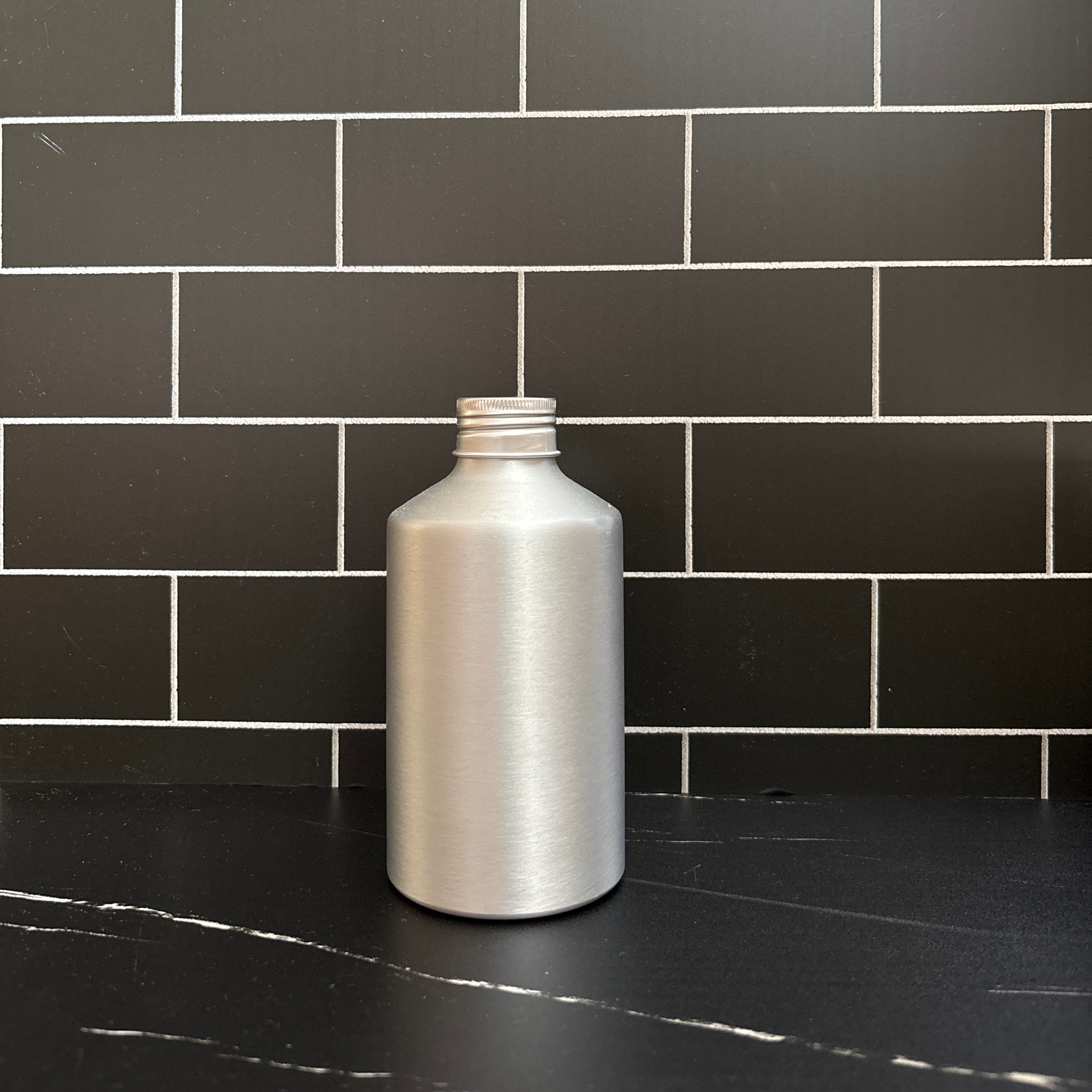Aluminum bottle cap on a black tiled wall