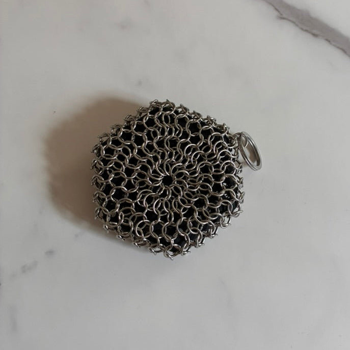 Cast Iron Scrubber on a marble surface made of stainless steel and silicone