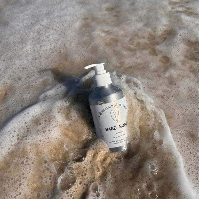 Hand soap in aluminum bottle on a beach with waves