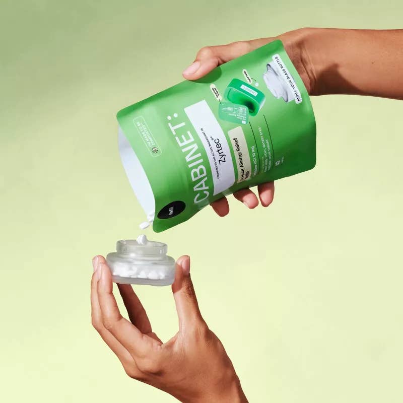 Person pouring a product from a green 'Cabinet' container onto their palm against a light green background