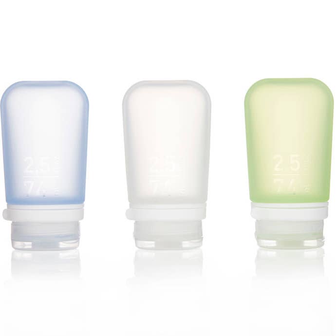 Three GoToob+ travel size silicone bottles in blue, white, and green, displayed side by side.