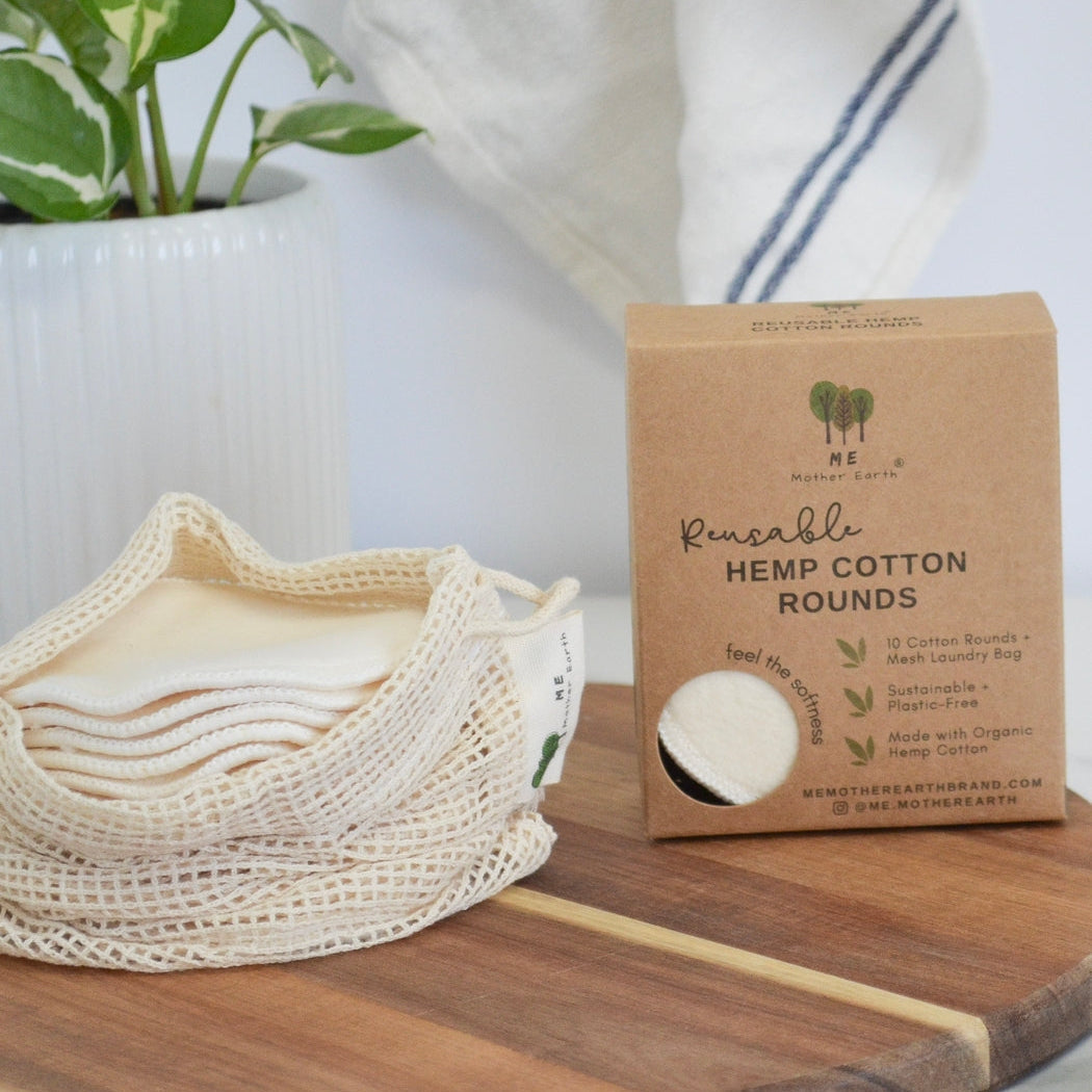 Pack of reusable hemp cotton rounds on a wooden surface with a plant in the background