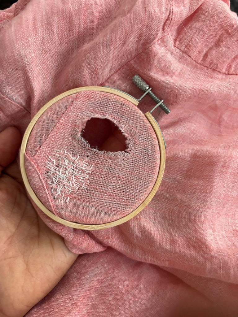 Person mending a garment by hand with needle and thread