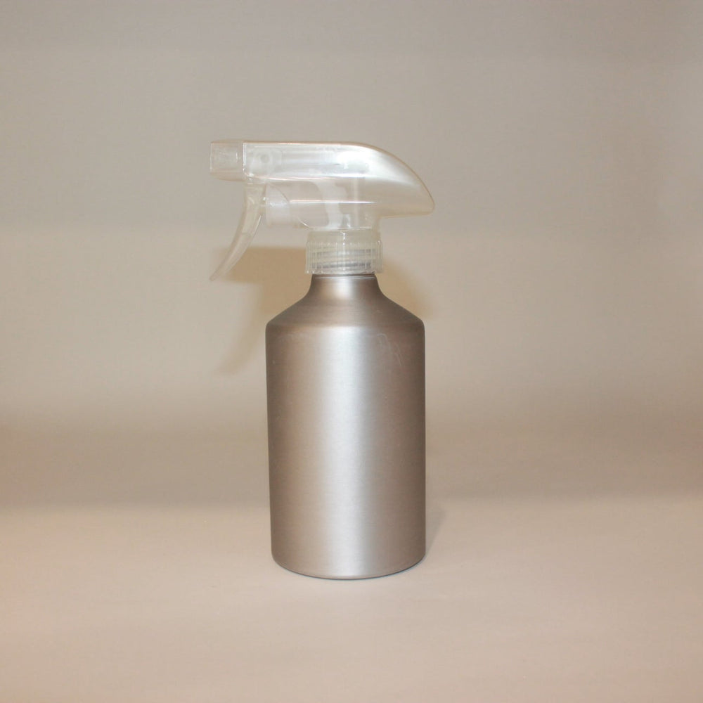 Silver spray bottle on a beige surface with a neutral background