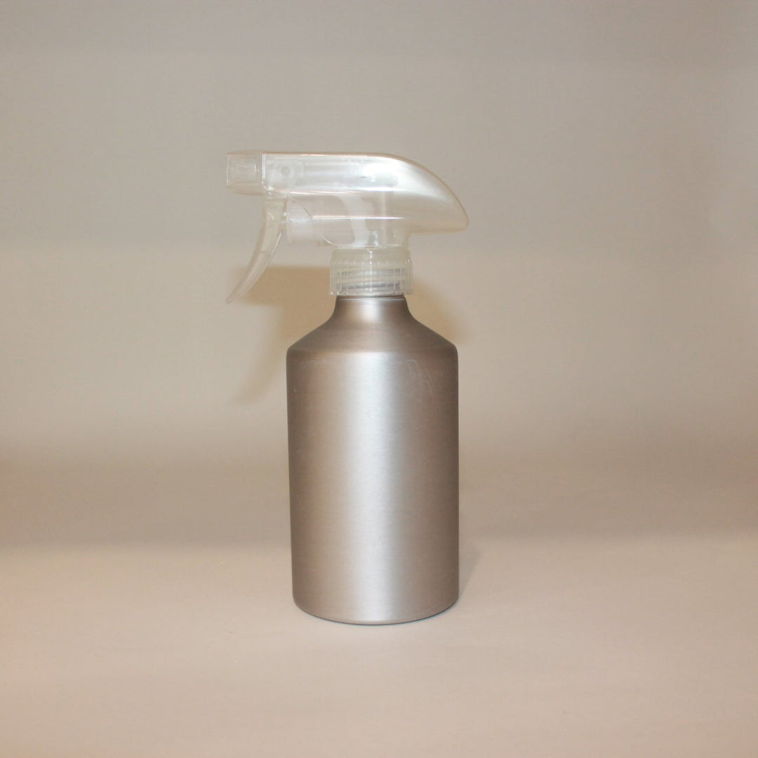 Silver spray bottle on a beige surface with a neutral background