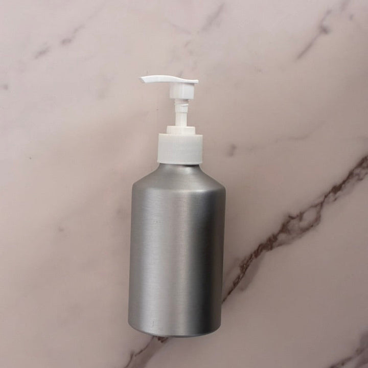 Silver soap dispenser with pump on a marble surface