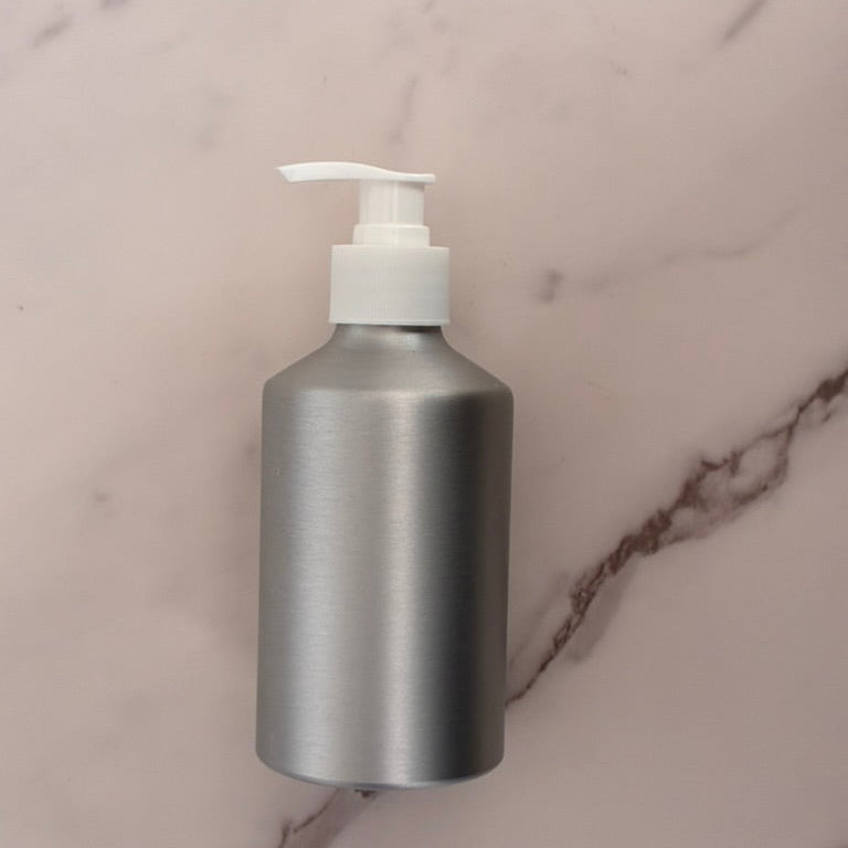 Silver bottle with a white pump on a marble surface