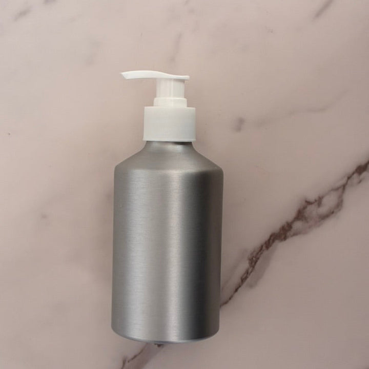 Silver bottle with a white pump on a marble surface