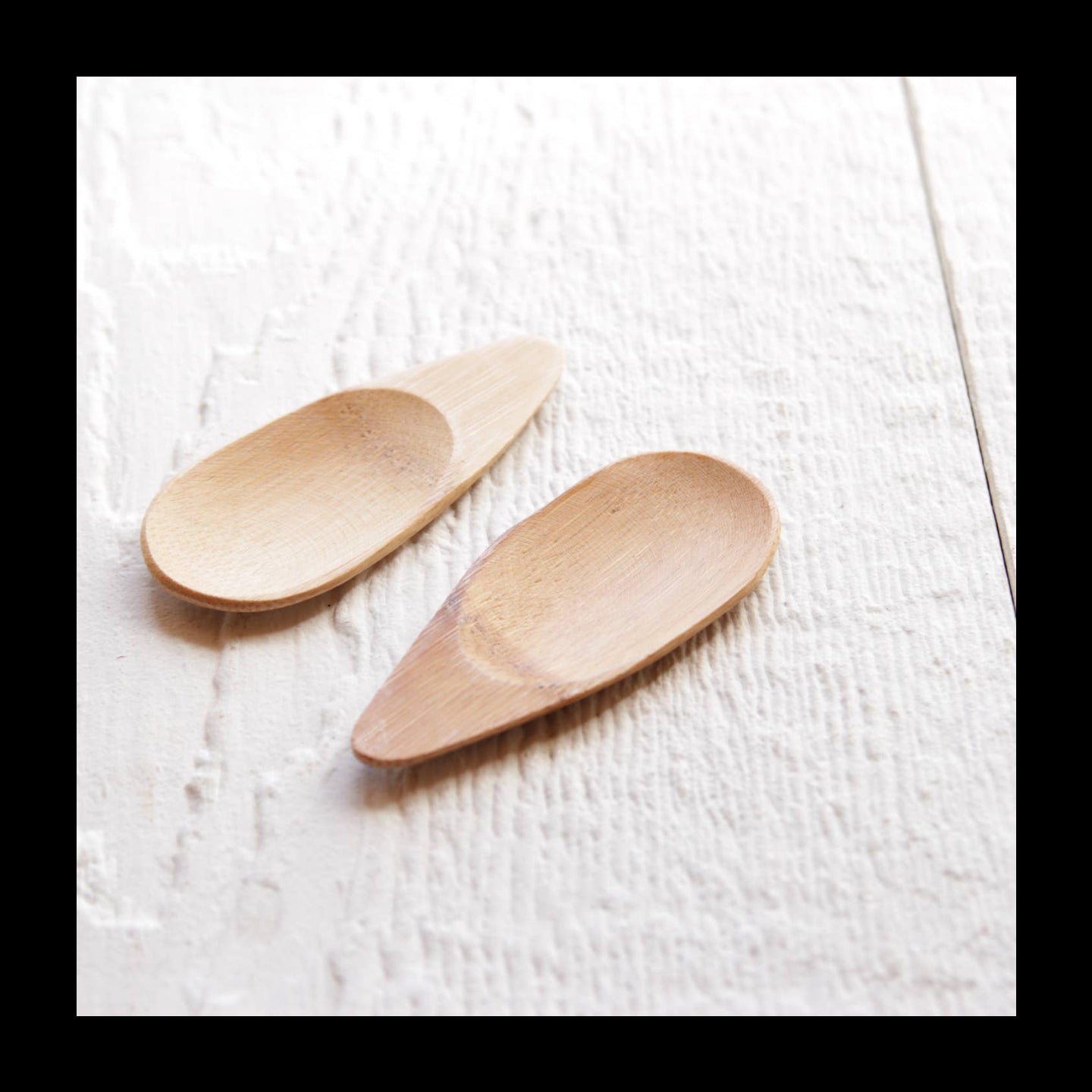 Two wooden spoons on a textured white surface