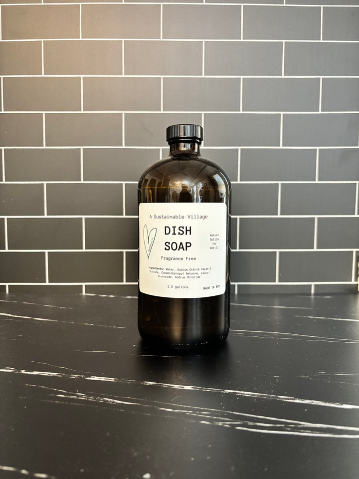 Bottle of dish soap on a black countertop with a tiled wall background refill zero waste plastic free glass bottle 32 oz