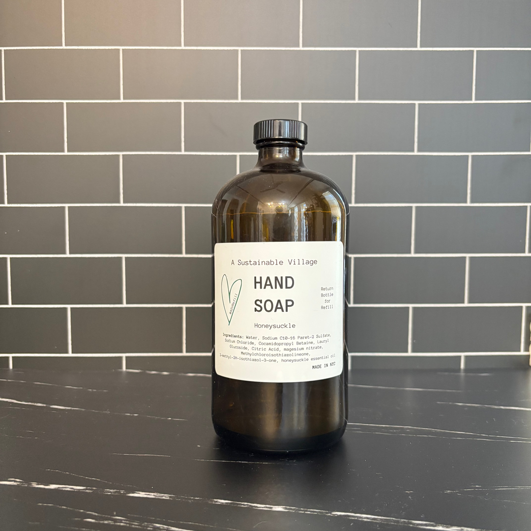 Bottle of hand soap on a black countertop with a tiled wall background refill zero waste 32 oz glass amber