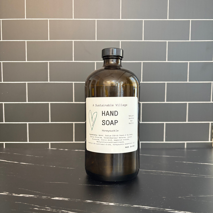 Bottle of hand soap on a black countertop with a tiled wall background refill zero waste 32 oz glass amber
