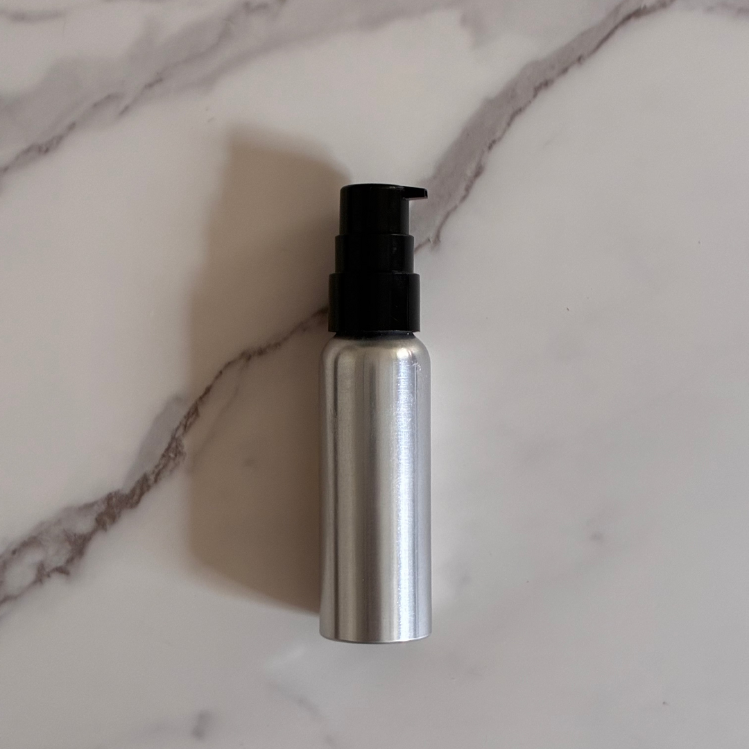 Aluminum bottle with black pump on a marble surface for refilling