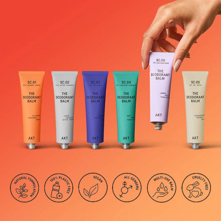 Collection of colorful deodorant balm tubes with a hand holding one, on an orange background. Plastic Free Zero Waste Taylor Swift favorite