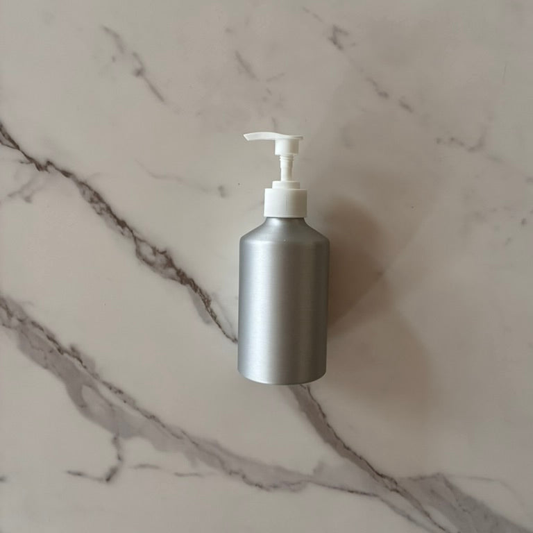 Aluminum pump bottle for refill of soap or lotion  on a marble surface, plastic free, plastic detox