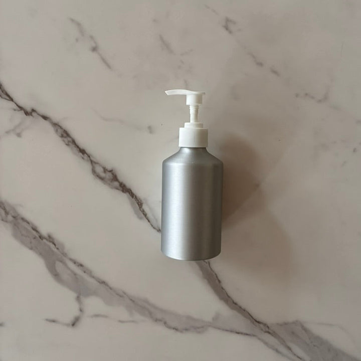 Aluminum pump bottle for refill of soap or lotion  on a marble surface, plastic free, plastic detox
