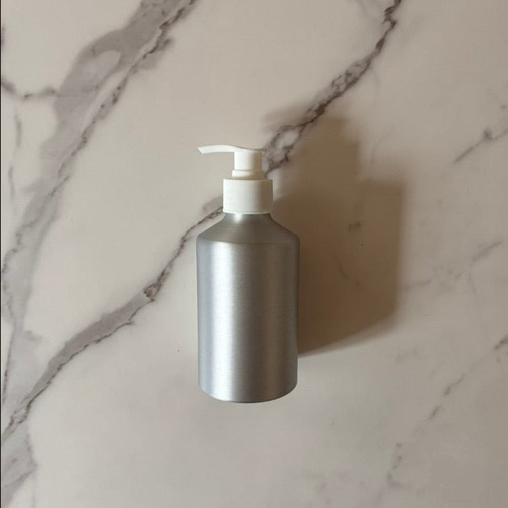 Aluminum pump bottle for refill of soap or lotion on a marble surface