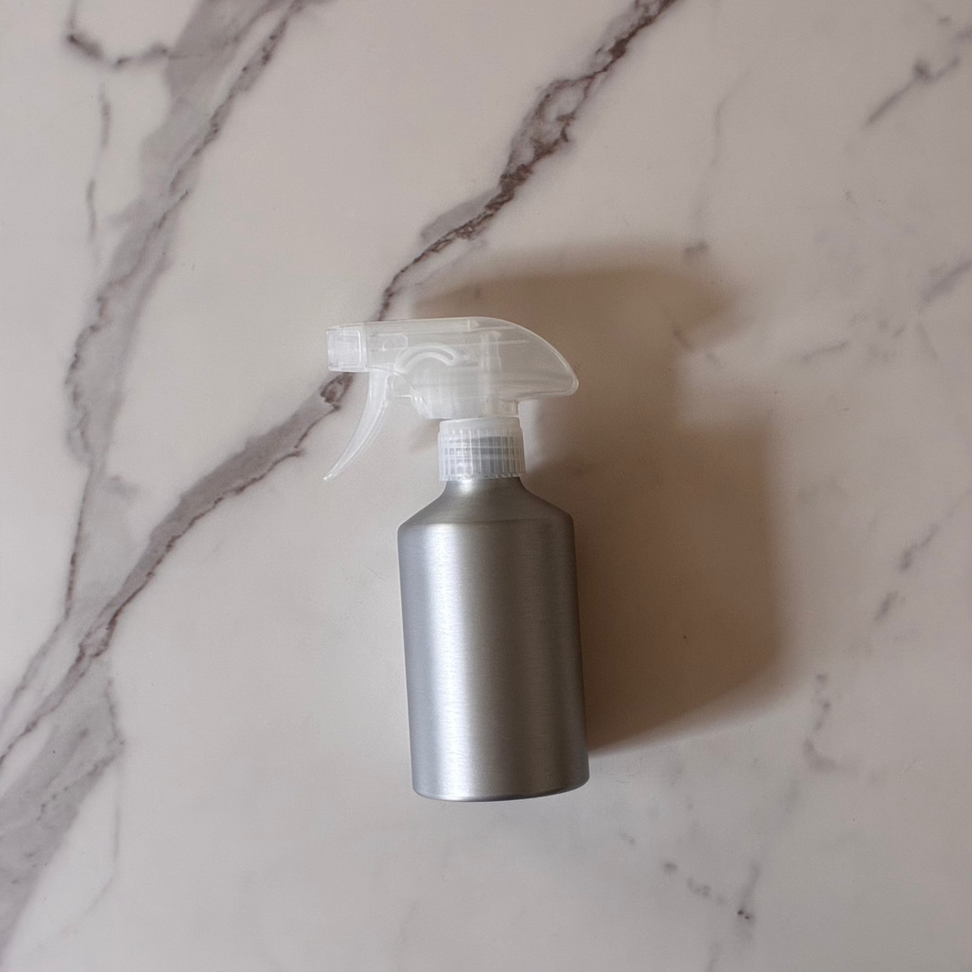 Aluminum spray bottle for refill on a marble surface