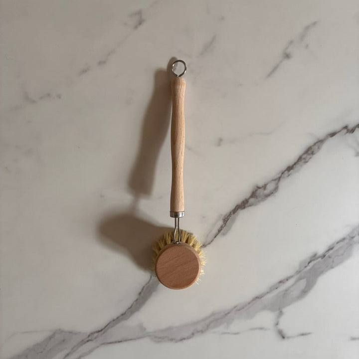 Natural dishwashing brush with wooden handle on a marble surface for a plastic free kitchen