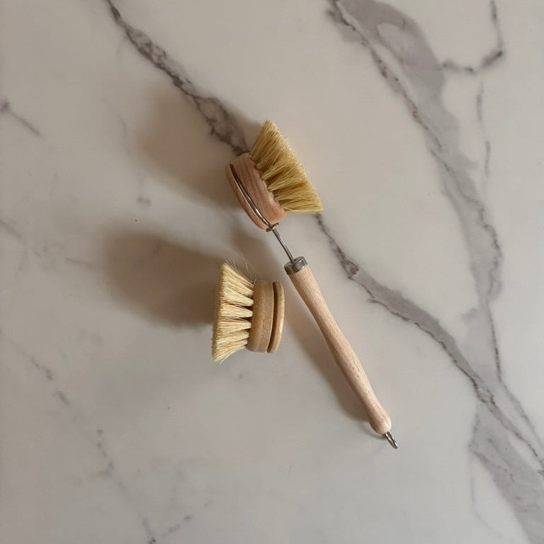 Two wooden dish brushes on a marble surface