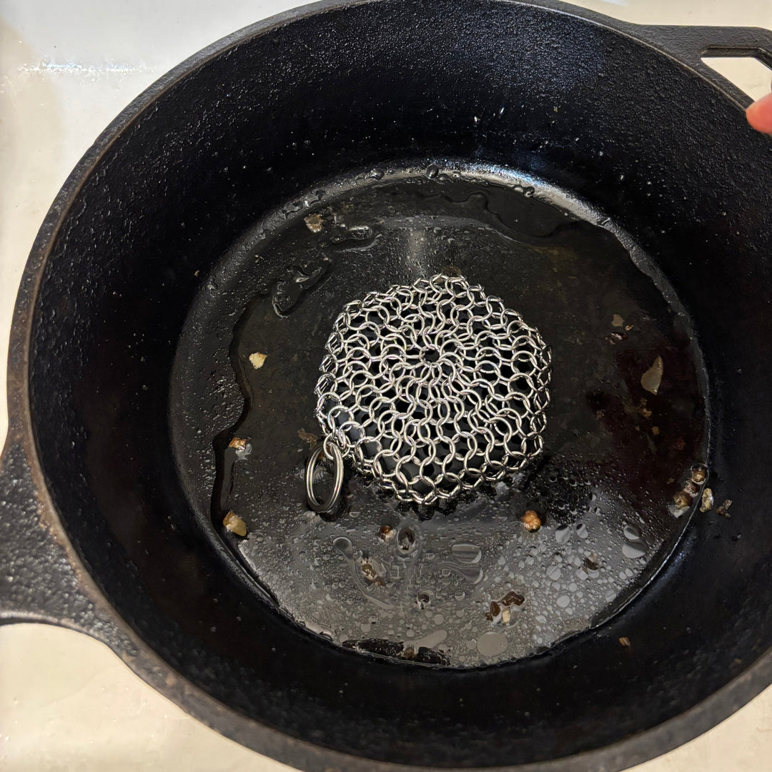 Black cast iron skillet chain sponge with a textured surface on a white background