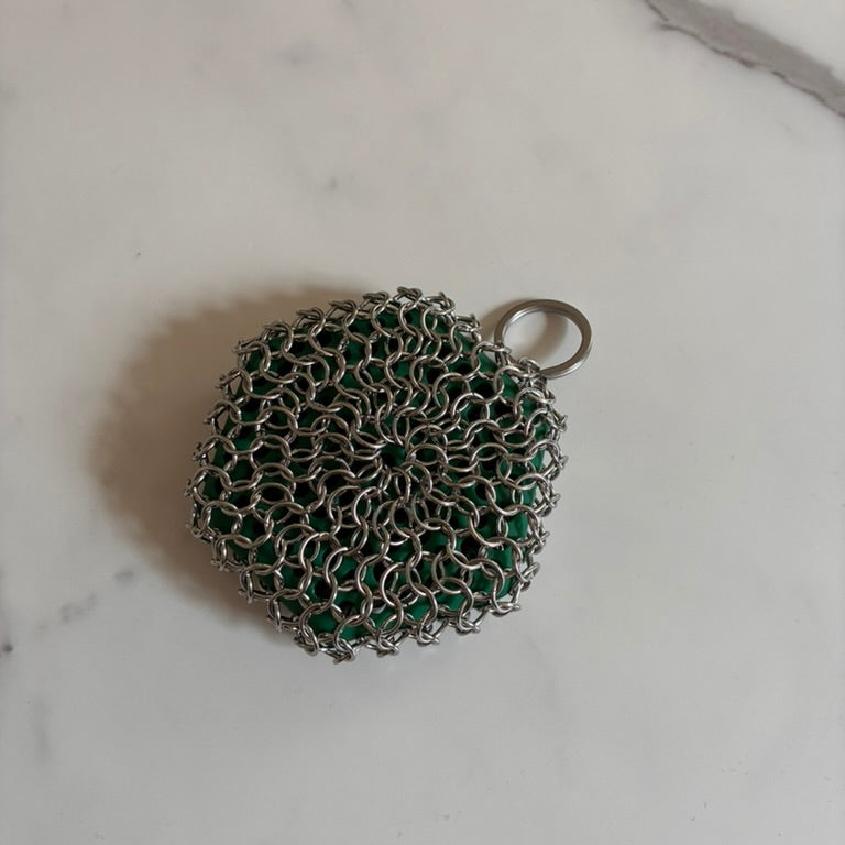 Cast Iron silver and green scrubber on a marble surface