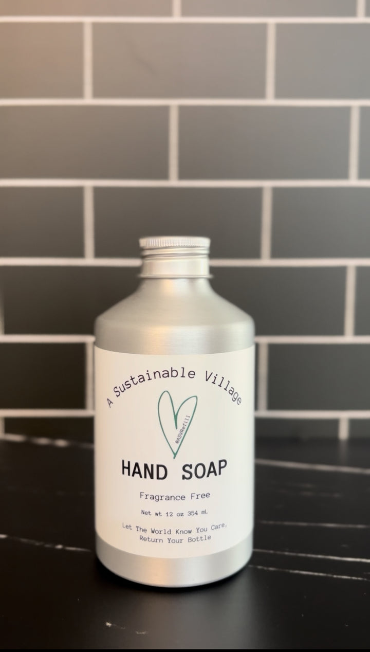Fragrance Free Hand soap bottle with 'Sustainable Village' label on a tiled wall background plastic free