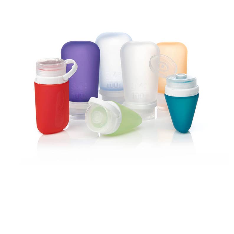 A collection of GoToob+ containers in various colors displayed with their caps off, showcasing the food-grade silicone body and the leakproof valve in the cap.