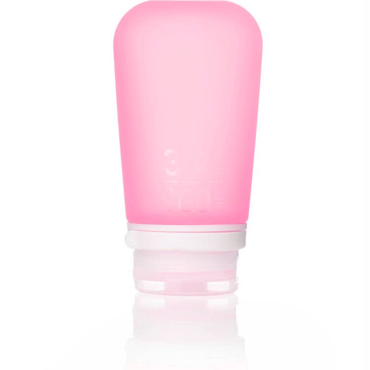 A collection of GoToob+ containers in various colors displayed with their caps off, showcasing the food-grade silicone body and the leakproof valve in the cap.
