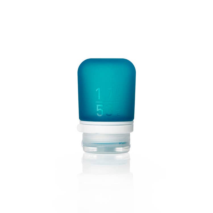 A collection of GoToob+ containers in various colors displayed with their caps off, showcasing the food-grade silicone body and the leakproof valve in the cap.