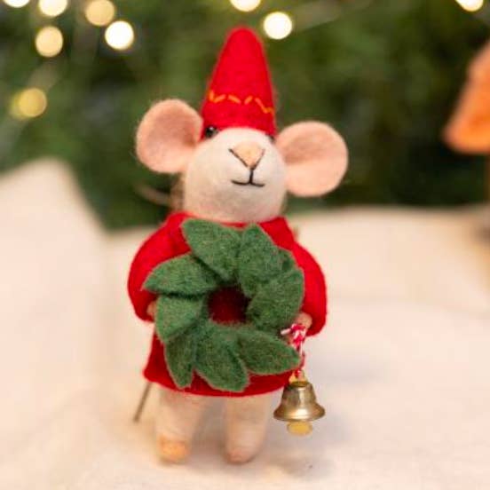 Felt mouse ornament wearing a red outfit with a green wreath and gold bell, against a blurred festive background.