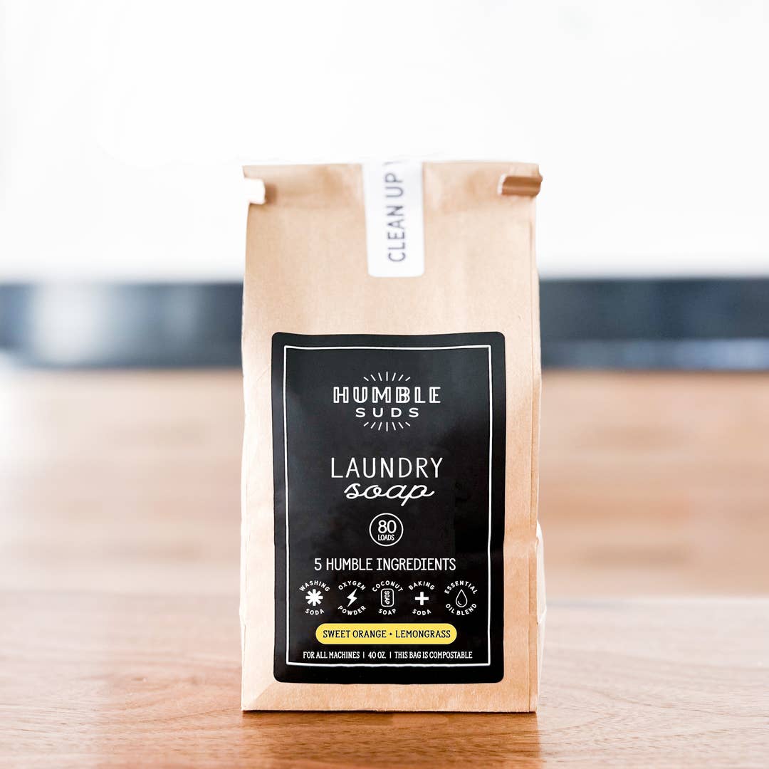 Kraft paper bag of Humble Suds laundry soap on a wooden surface with a blurred background