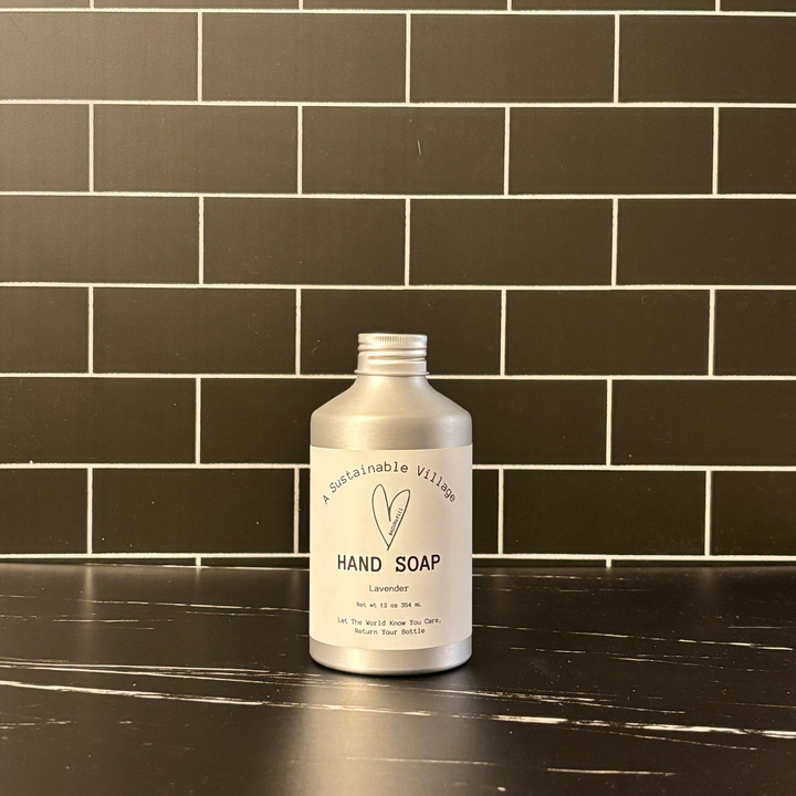 Hand soap bottle on a black countertop with a tiled wall background