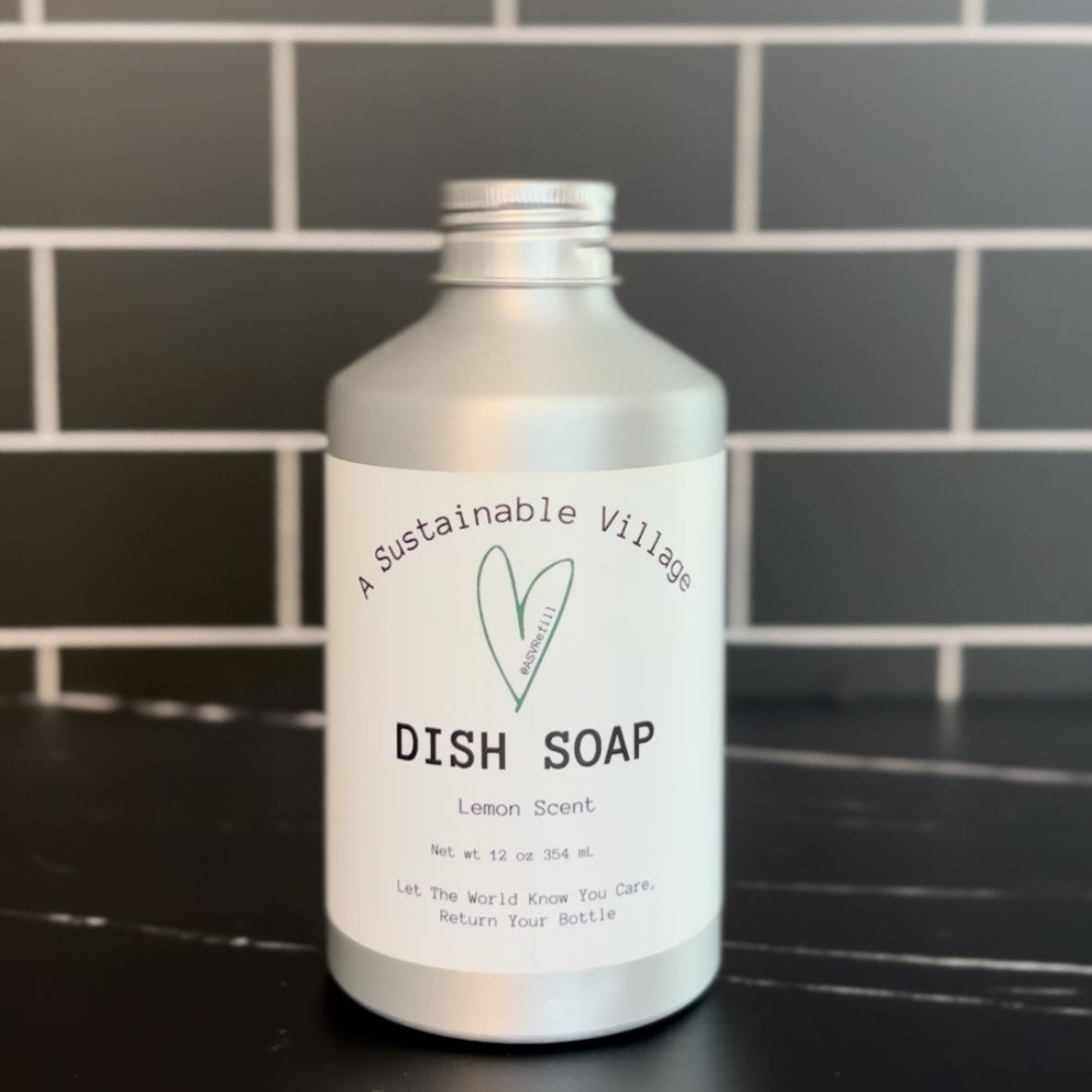 Bottle of lemon dish soap on a black countertop with a tiled wall background refill zero waste plastic free aluminum bottle