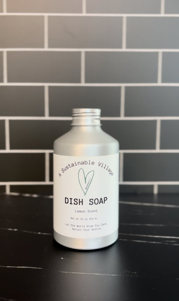 Bottle of lemon dish soap on a black countertop with a tiled wall background refill zero waste plastic free aluminum bottle