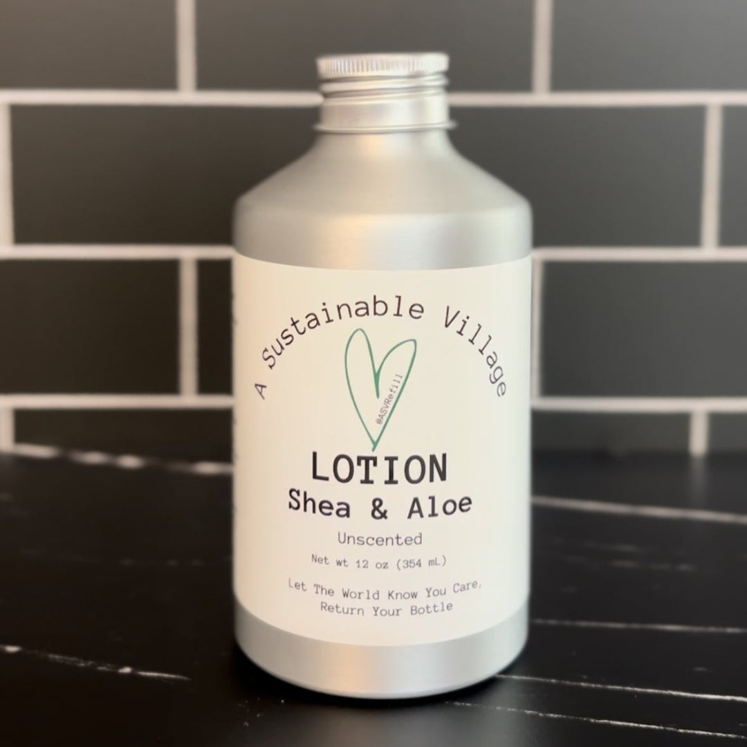 Bottle of lotion labeled 'Shea & Aloe' on a black surface with a tiled wall background.