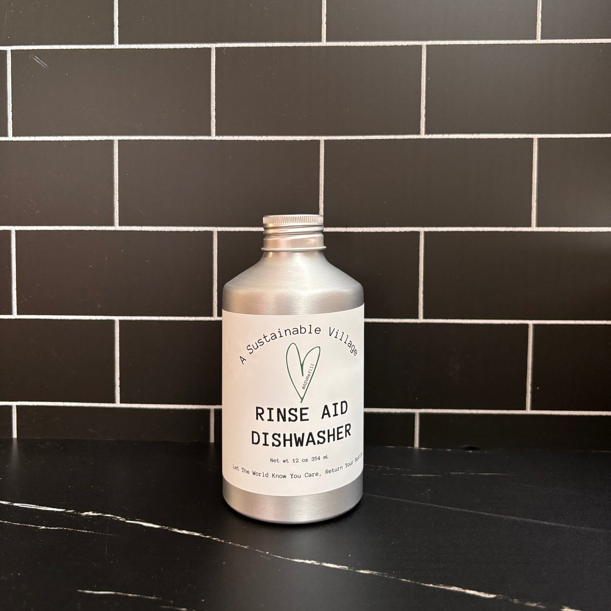 Silver bottle of rinse aid dishwasher on a black tiled kitchen counter