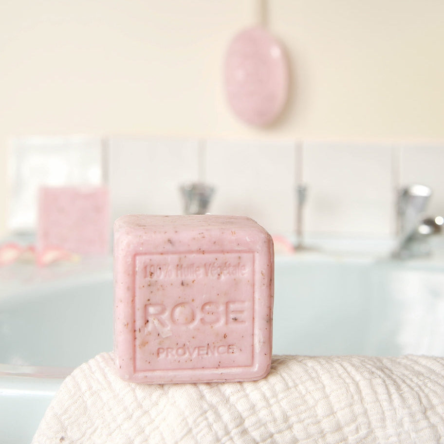 Pink soap bar with 'Rose Provence' text on a textured surface, blurred background