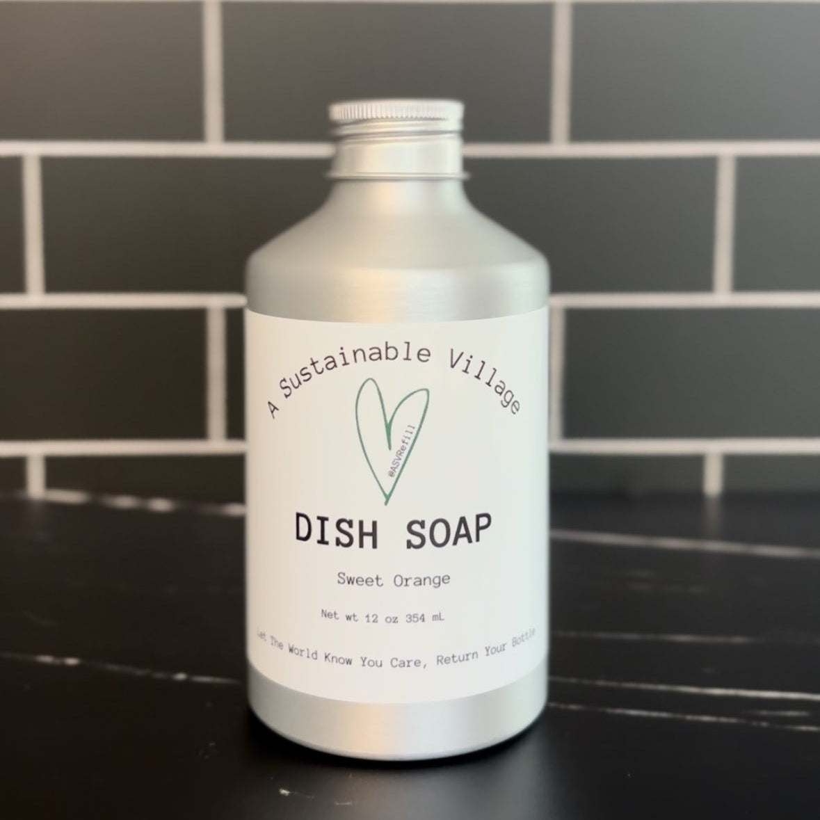 Bottle of dish soap on a kitchen counter with a tiled wall background Sweet Orange refill aluminum bottle