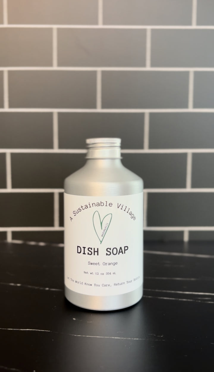 Bottle of dish soap on a kitchen counter with a tiled wall background Sweet Orange refill aluminum bottle